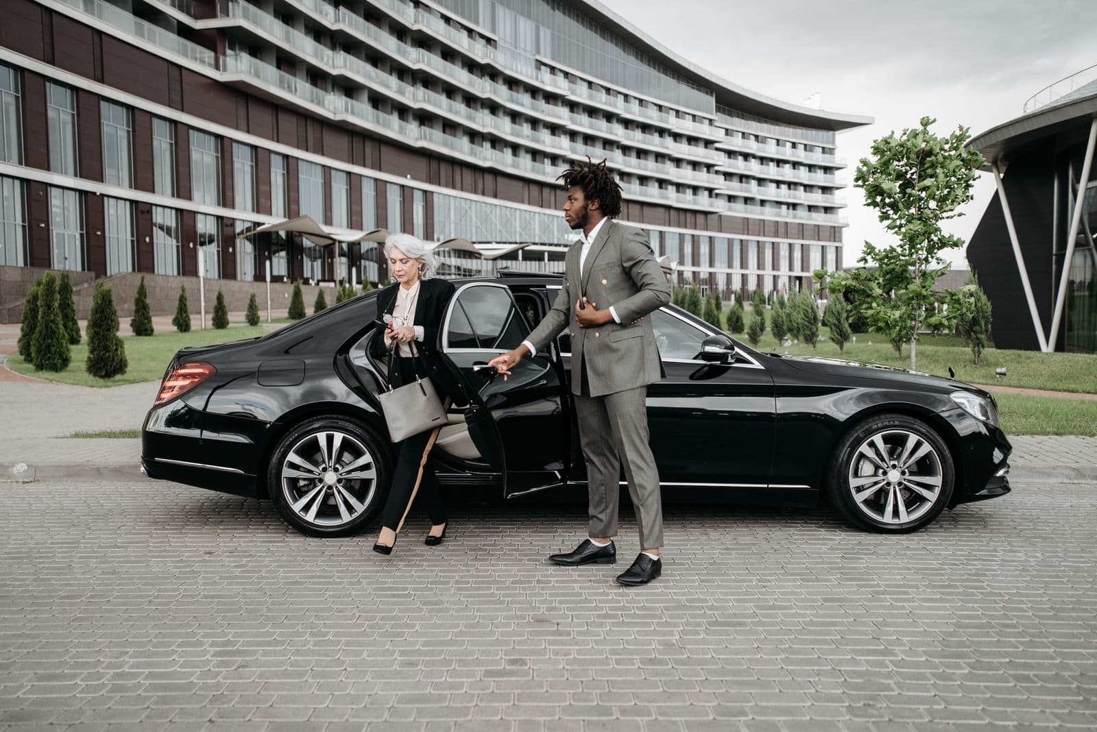 Chauffeur assisting a passenger from an executive car