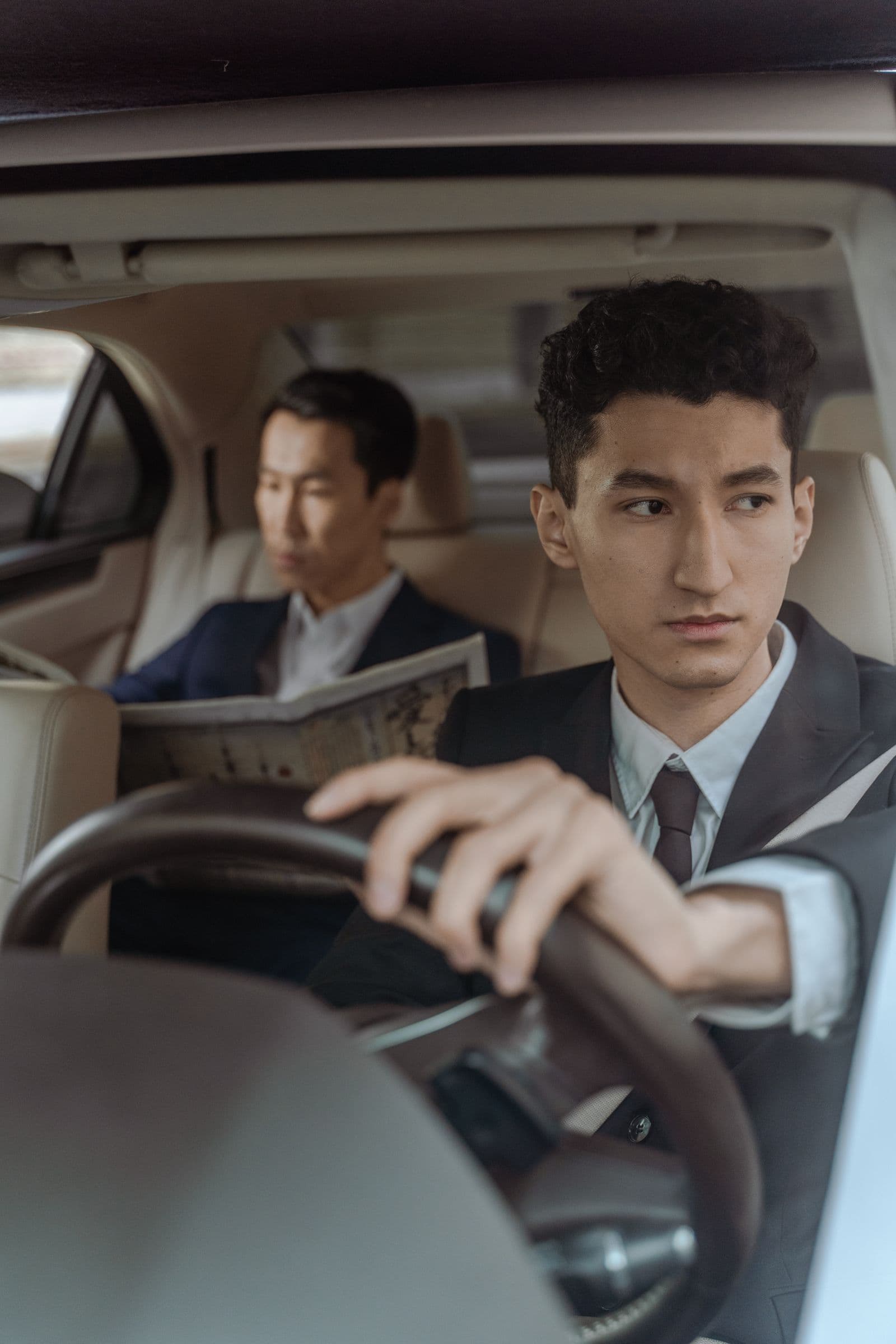 Principal reading a newspaper in the back of a chauffeured car
