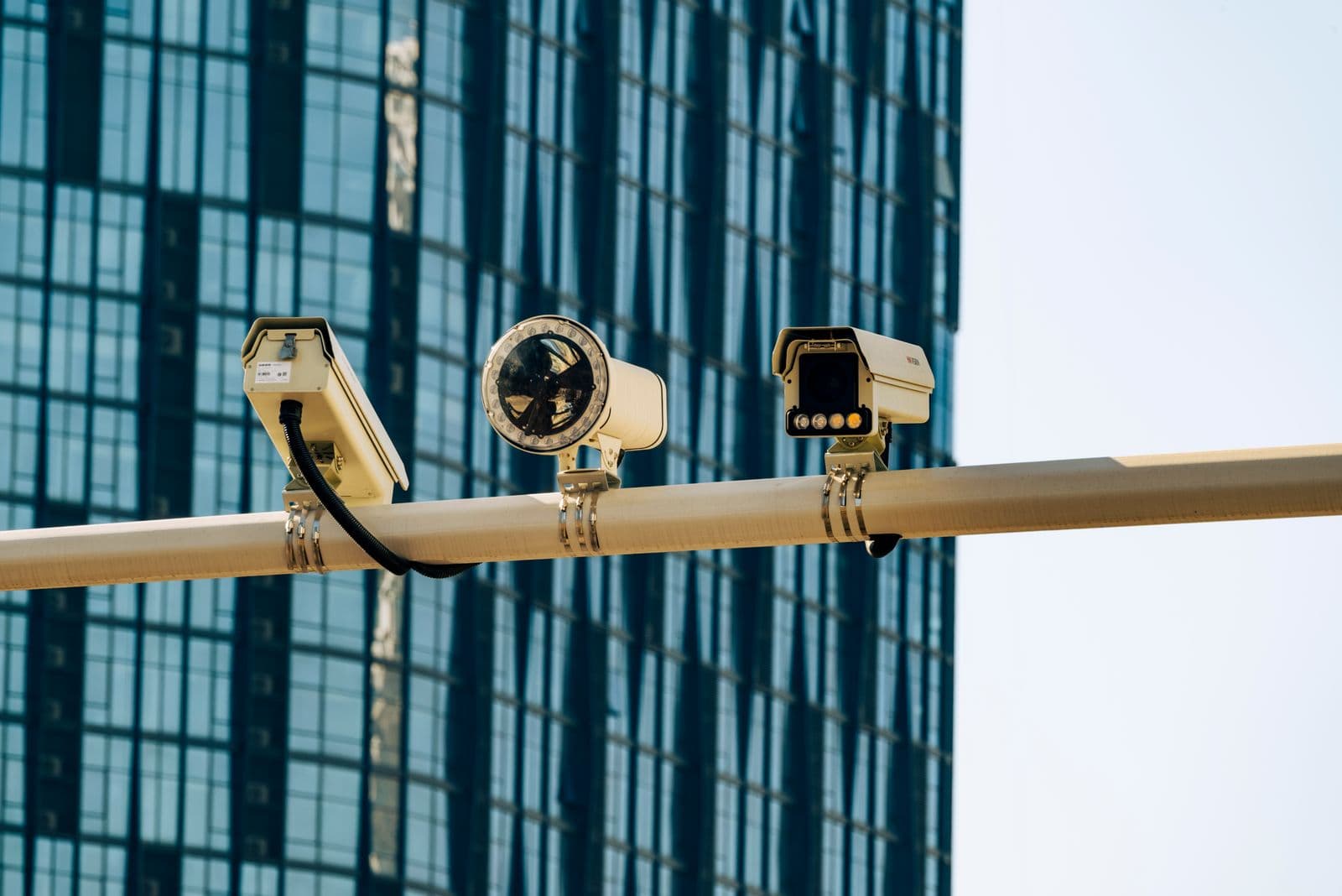 Security cameras mounted against a modern glass building